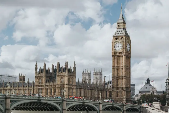The Palace of Westminster and the Elizabeth Tower seen from Westminster Bridge under a cloudy sky.